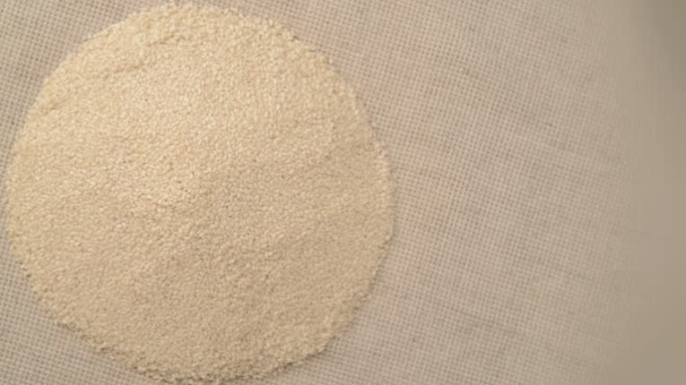 Nuts sesame turn on the turntable. The subject background is spinning and moving. The camera is static. On the table is a linen cloth bag.